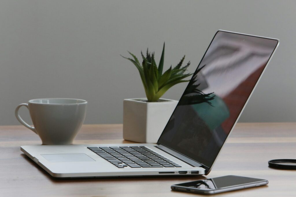 Free Minimalist home office desk with laptop, smartphone, and plant for a modern work environment. Stock Photo